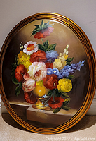 Full view of the oval oil painting showing the vibrant floral bouquet in a yellow vase with a gold-toned frame.
