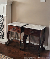 Pair of side tables angled view showing overall shape, marble tops and wood bases.