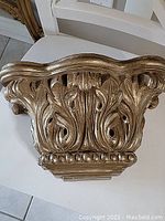 Front view of decorative wall bracket highlighting the detailed carved leaf and floral design.