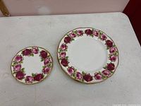 Top view of two plates, one smaller and one larger, showing rose border and gold rim