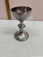 Front view of the 6 inch metal chalice trophy showing its shape and size with a ruler for scale.