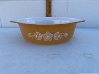 Photo of gold Pyrex dish with white butterfly floral design and handles, showing side view