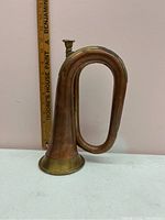 Full side view of copper bugle showing its looped construction and brass bell.