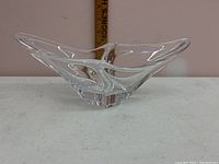 Front angle of one Daum French crystal bowl showing its clear glass and unique shape with ruler in background