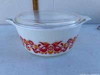 Side view showing the Friendship pattern of red and orange birds and flowers on the white glass Pyrex casserole dish, with lid in place.