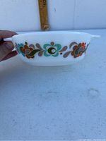 Side profile showing the colorful floral pattern around the dish and molded handles