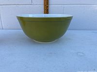 Side view of olive green Pyrex mixing bowl showing shape and color