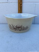 Front-side photo of a small Pyrex glass dish showing mushroom pattern with a ruler for size reference.