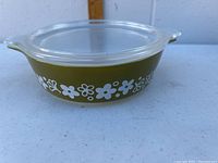 Photo of Pyrex Spring Blossom small casserole dish with lid, showing olive green glass with white floral design and handles.