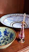 View showing two bowls and a vintage perfume bottle on a wooden shelf.