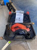 Black & Decker planer in black plastic carrying case with instruction manual and coiled power cord visible.