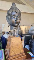 Front view of Buddha head sculpture on wooden base