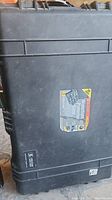Front view of black Pelican watertight protector case showing label and surface wear.
