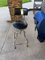 Full view of adjustable Craftsman garage stool with black padded round seat, backrest, and chrome frame.