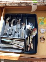 Drawer tray containing sets of forks, spoons, and serving utensils placed side by side.