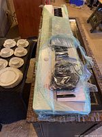 Casio Previa PX-130 keyboard wrapped in plastic on a table with a power cable on top.