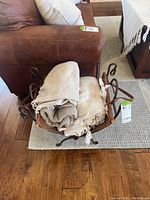 Wrought iron and leather magazine holder filled with folded blankets and throws, showing usage and potential alternative uses.