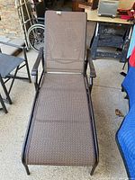 Full view of the patio lounger chair showing metal frame and brown mesh fabric surface.