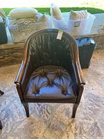 Front view of barrel-back arm chair showing tufted leather and wood frame