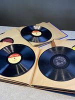 Photo showing multiple 10" shellac 78 RPM records inside vintage album sleeves with labels including Quality and Decca.