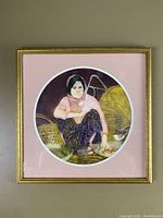 Circular print of Cambodian woman seated, matted in pink and framed in gold-tone metal.