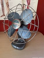 Close-up image of Electrohome industrial cage fan showing metal blades, protective cage, and brand badge on the blade hub.