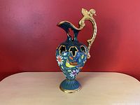 Full view of the large Hubert Bequet pitcher vase showing green background, floral and bird decoration, gold handle and base rim