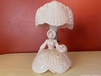 Front view of the pink Art Deco boudoir lamp featuring the woman figurine base and the clamshell shade.