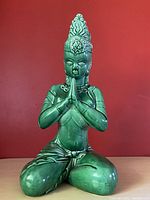 Front view of the green ceramic praying goddess statue showing detailed face, hands together in prayer, and headdress.