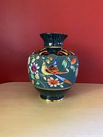 Front view of the vase showing the bird and floral decorative pattern with green background and gold accents.