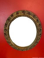 Front view of vintage oval mirror with intricate gold frame and clear glass.