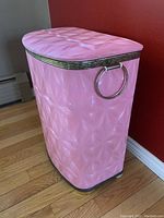 Full view of vintage pink hamper basket with textured vinyl exterior, metal rims, and side handles.