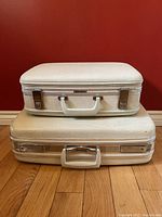 Front view of two stacked vintage white hardshell suitcases, smaller Birkdale on top, larger Travelgard below