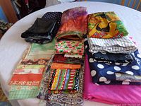 Photo showing folded fabric pieces including black, purple, orange, multicolor, floral, checkered, polka dot, and striped patterns.