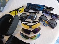 Full assortment of 12 glasses including 3D and multiple sunglasses on white surface, some with cases