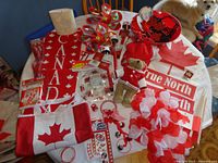 Photo showing the majority of Canada Day items on a table including flag tote bag, leis, headbands, stuffed bear, and banners