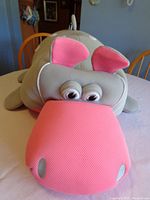 Front view showing the large pink textured snout and gray body with eyes and ears of the hippo pool toy lying on a table.