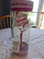 Photo of wine glass in clear decorative packaging showing pink stem, 'Drama Queen' text and packaging details.