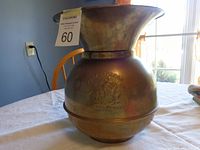 Full view of the metal spittoon on a white table with window light behind.
