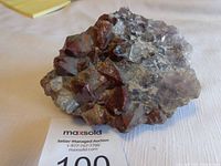 View of the crystallized mineral rock specimen showing large reddish-brown shiny crystals on rough rocky base.