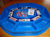 Top view of blue Rummoli game tray with compartments and playing card graphics, plastic chips in center compartment inside a bag, auction lot card visible