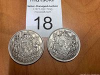 Top side of two Canadian 50 cent coins dated 1943 and 1940 showing Canadian coat of arms with lions and crown