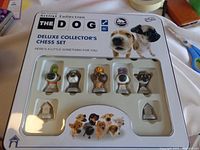 Front of the chess set packaging showing six individual dog-themed chess pieces inside a plastic tray with the set branding and dog photos on the box cover.