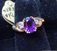 Top view of ring on black velvet insert showing oval purple amethyst and gold setting