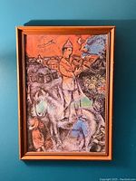 Full view of framed artwork depicting man on horse holding bird in front of houses