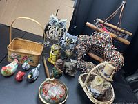 Photo of multiple owl and bird figurines with various decorative items including basket, wreath, and wooden pieces.