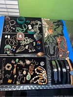 Full overview of all jewelry showing trays with necklaces, bracelets, earrings, brooches and six wristwatches.