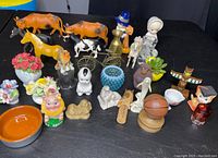 Various figurines including horses, cows, ceramic flowers, basketball, and other decorative items arranged on a table.