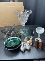 Overview photo showing entire lot including glass vases, plates, bowl, candy dish, and salt and pepper shakers arranged on black surface
