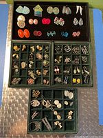 Full view of the earring collection displayed in three green partitioned trays showing various styles and colors